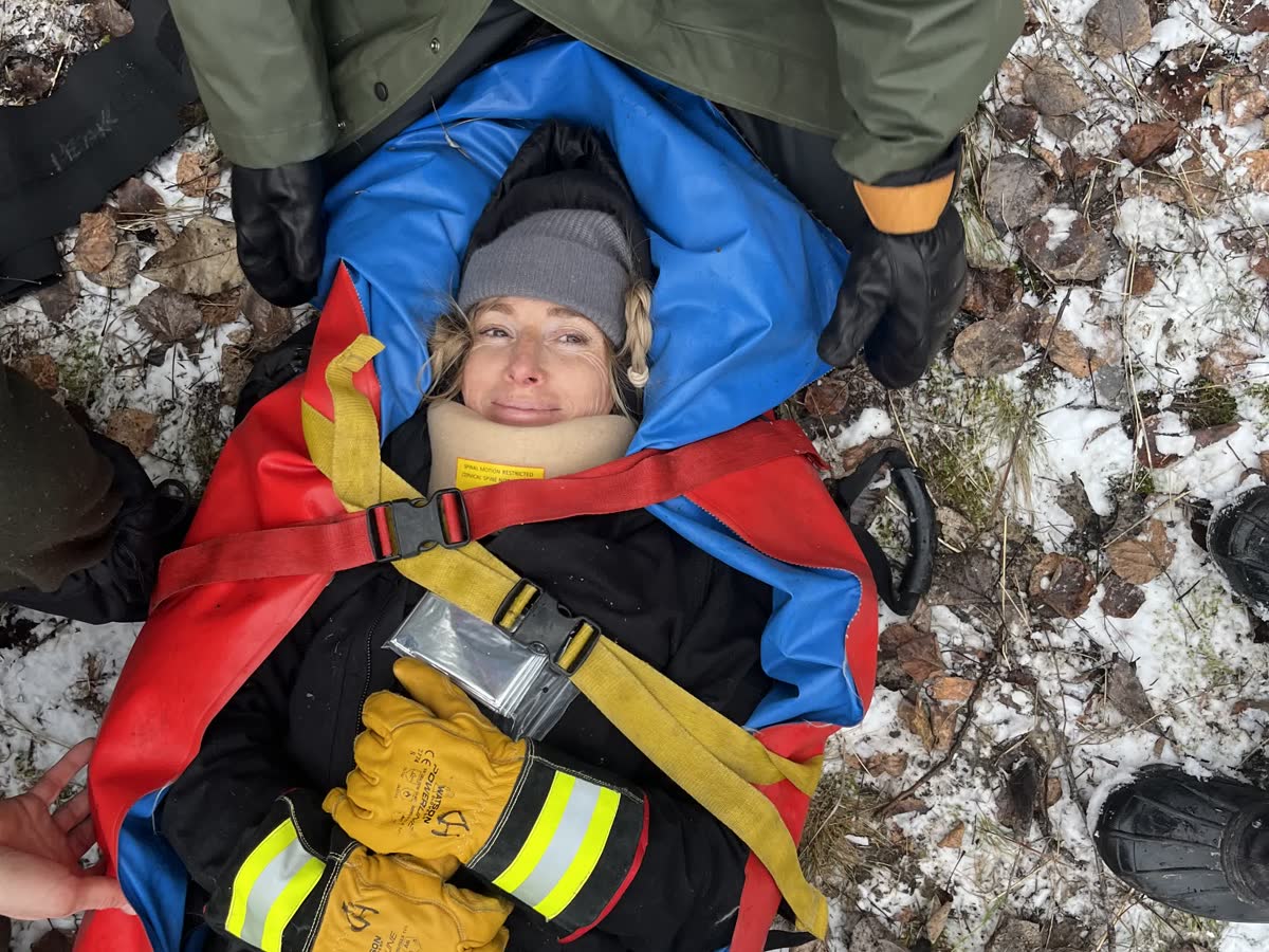 A packaging and extrication training scenario in the snow, with a patient secured in a vacuum splint and cervical collar.